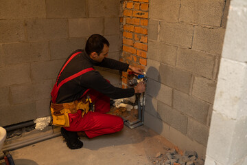 Fototapeta premium building, profession and people concept - builder or plumber working with water pipes in boiler room