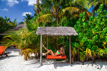 Beautiful sexy tanned woman in bikini on Maldives island. Young glamour girl in swimsuit on Maldives beach. Perfect body bikini model in luxury resort on Maldives. Bikini fashion. Luxury travel.