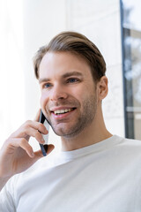 portrait of young man smiling during conversation on mobile phone.