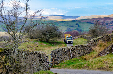 Rural highway maintenance road maintenance repair work on potholes on country lane tarmac asphalt in Lake District, England