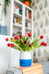 A bouquet of red tulips in a vase on the table in the modern living room. Beautiful spring concept