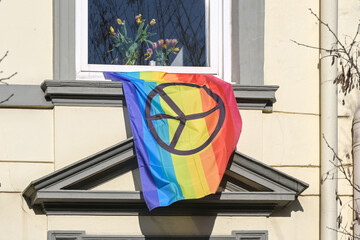 Rainbow flag with peace sign hanging out of a window on the facade of a house