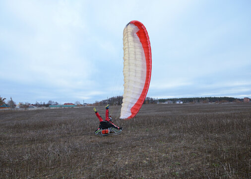 Man paramotorist and paramotor falling down on the ground in the field