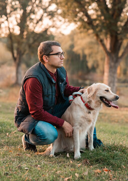 Young man hugging golden retriever dog in autumn outdoors