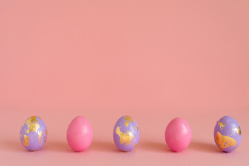 Fototapeta na wymiar Easter eggs, pink and violet with golden foil on pink background, copy space.