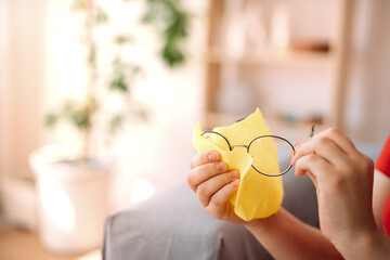 the girl manually cleans the lenses of glasses at home, the concept of cleaning glasses.