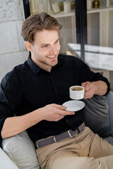happy and stylish man sitting with morning coffee at home.