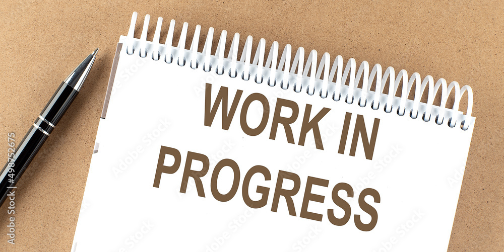 Poster work in progress text on a notepad with pen, business concept