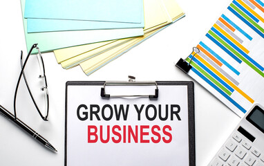 GROW YOUR BUSINESS text on the paper sheet with chart,color paper and calculator