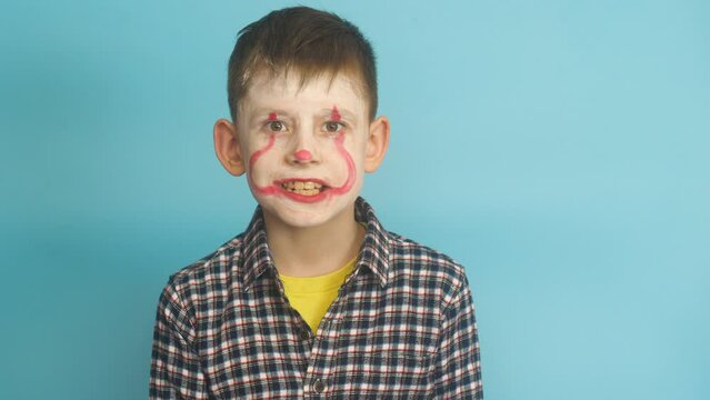 Caucasian scary boy 7-8 years old because of a balloon with a terrible monster grimm. Studio shot on a blue background. Child playing horror movie monster