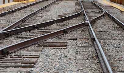 metal railroad tracks straight and curved lines converging into each other off into the  distance stones at base of tracks and metal clamps holding them down creating shapes and pattern horizontal  