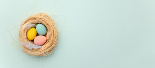 Happy Easter card. colored pink easter eggs on a blue nest background from above, image with...