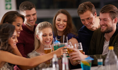 Cheers to Friday night. Shot of a happy group of friends having drinks at a bar together.