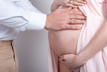 Pregnant woman and her husband close-up hands on a white background in the studio