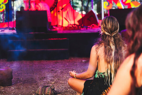 Long haired blonde girl at a new-age festival at an ethnic music concert sitting cross-legged