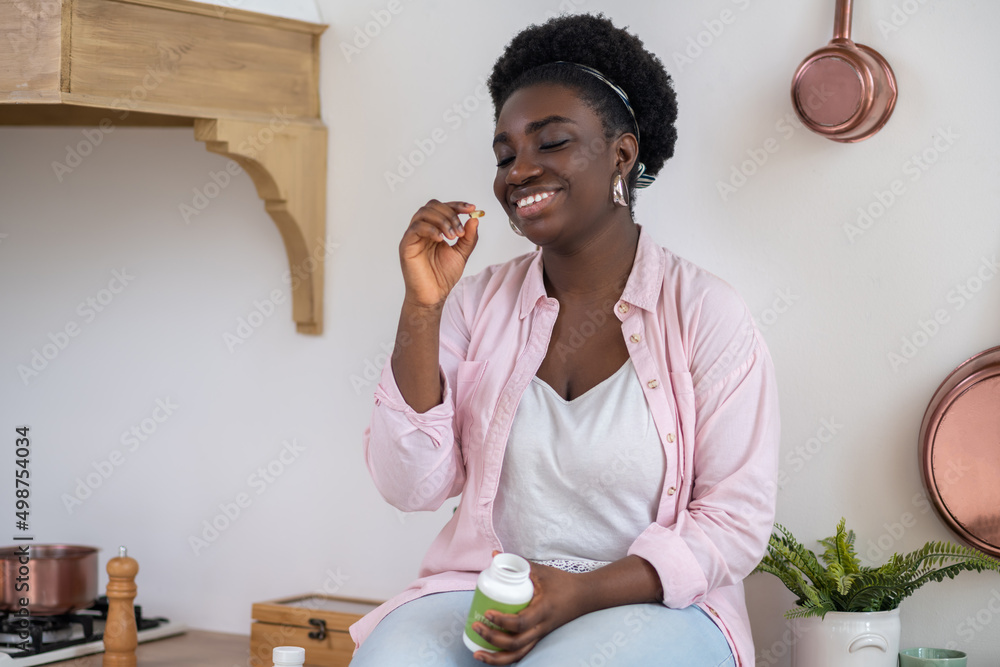 Wall mural african woman sitting on the table with pills in hands