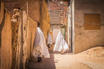 Muslim women on the narrow street of ancient Gardaia city, M'Zab valley, Algeria - obrazy, fototapety, plakaty