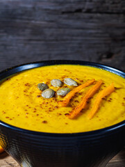 Pumpkin and carrot and chickpeas Cream soup on rustic wooden table.