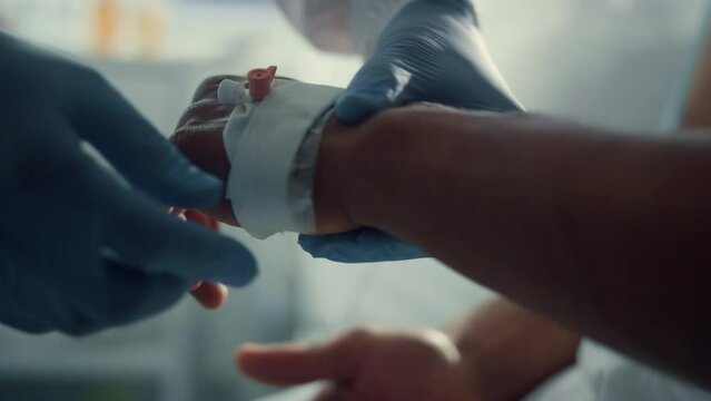 Patient hand with iv catheter closeup. Medical worker preparing drip equipment.