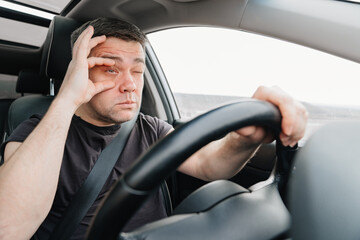 a sleepy man with closing eyes drives a car on the highway