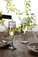 Dry white wine is poured into glasses on a summer terrace on a wooden table.