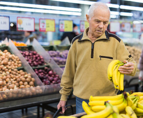 senor man pensioner buying banana in grocery in supermarket