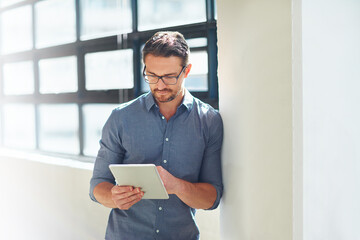 Hes a tech-savvy businessman. Cropped shot of a businessman working on his tablet in the office.