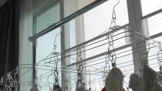 Indoor clothes laundry by hanging underwear pants and socks on aluminium hanger on sunny day