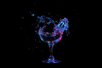 Glass with a splash of liqueur isolated on black background