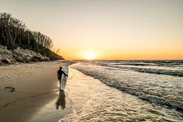 surfer na plaży w Jastrzębiej Górze nad Bałtykiem, podczas zachodu słońca