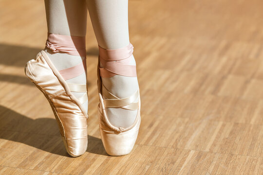 Ballet Pointe Shoes on feet on wooden floor background. Ballet Background