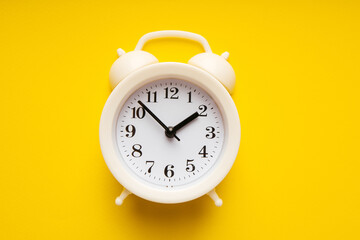 White alarm clock on a yellow background close-up