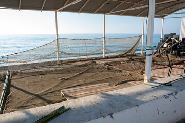 Fishing nets are dried under a canopy by the sea.