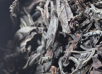 Dried black tea leaves as background.