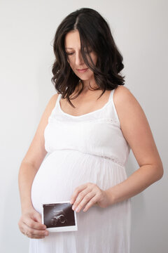 pregnant woman with a photo of ultrasound of pregnancy. enjoying pregnancy happy time. mother to be with cute big tummy