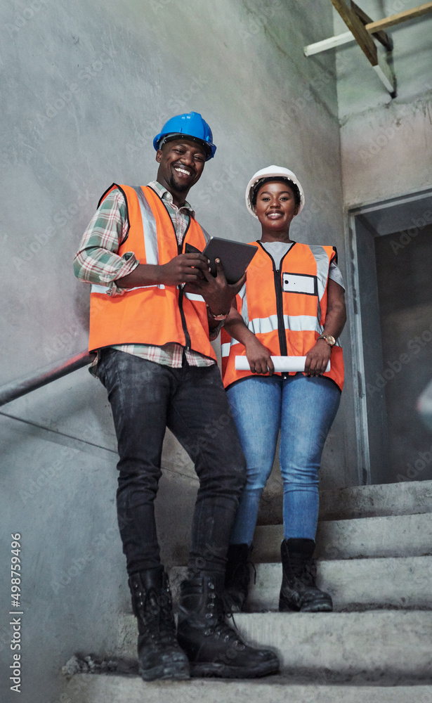 Poster killing it in the construction game. shot of a young man and woman using a digital tablet while work