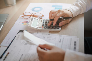 Close up hand of stress young asian businessman,male is pressing a calculator to calculate tax...