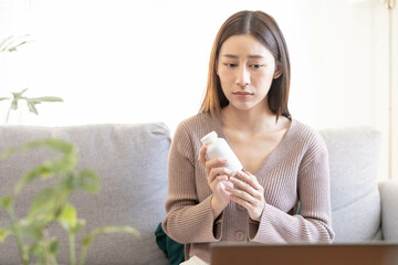 ickness asian young woman holding medicine bottle, consulting health by telehealth online with doctor about symptom stomach ache, use laptop computer. Telemedicine by medical for distance patient.