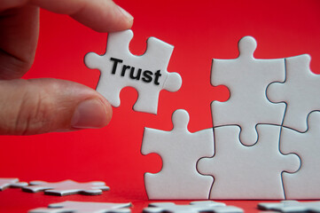 Trust text on jigsaw puzzle with red background - Working relationship and trust concept