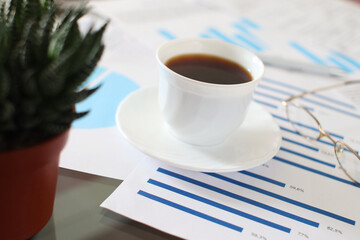 Obraz na płótnie Canvas A Cup of Coffee on Business Documents. Office work and break concept photography