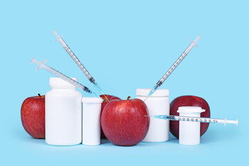 Apple fruits injected with syringes next to pill bottles. Concept for genetically modified food or...