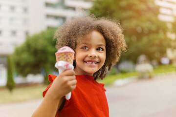 a happy black child with ice cream in a waffle cone at summer day