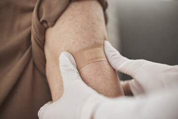 Making sure the area is protected. Closeup shot of an unrecognizable nurse applying a bandaid to a...