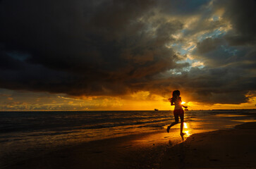 Obraz na płótnie Canvas person walking on the beach at sunset