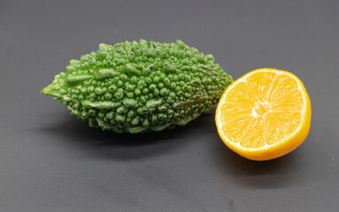 bitter melon or bitter gourd with orange isolated on black background
