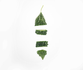 bitter melon or bitter gourd slices falling isolated on white background
