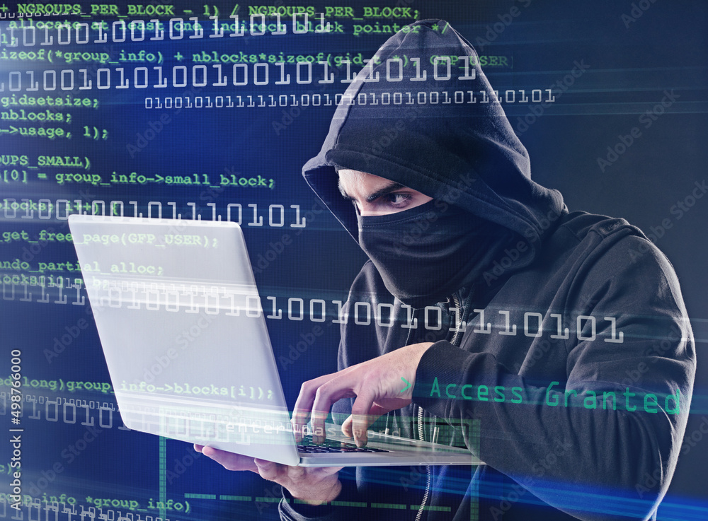 Fototapete hes about to crack the code. shot of a computer hacker using a laptop while standing against a dark 