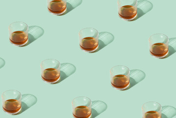 Pattern with Glasses Of Whiskey Or Scotch On mint Background. Creative sunny or shadow composition with alcohol drinks. Minimal pastel green color idea.