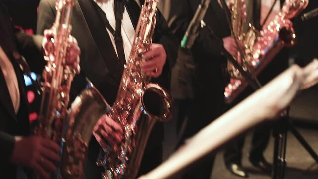 Concert view of saxophonist, a saxophone sax player with vocalist and musical during jazz orchestra performing music on stage 
