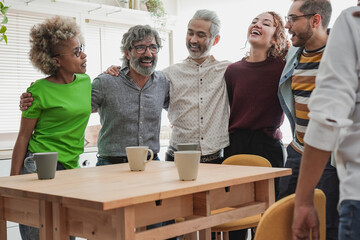 Happy multiracial people having fun at home kitchen hugging each other - Multi generational friends enjoy day together